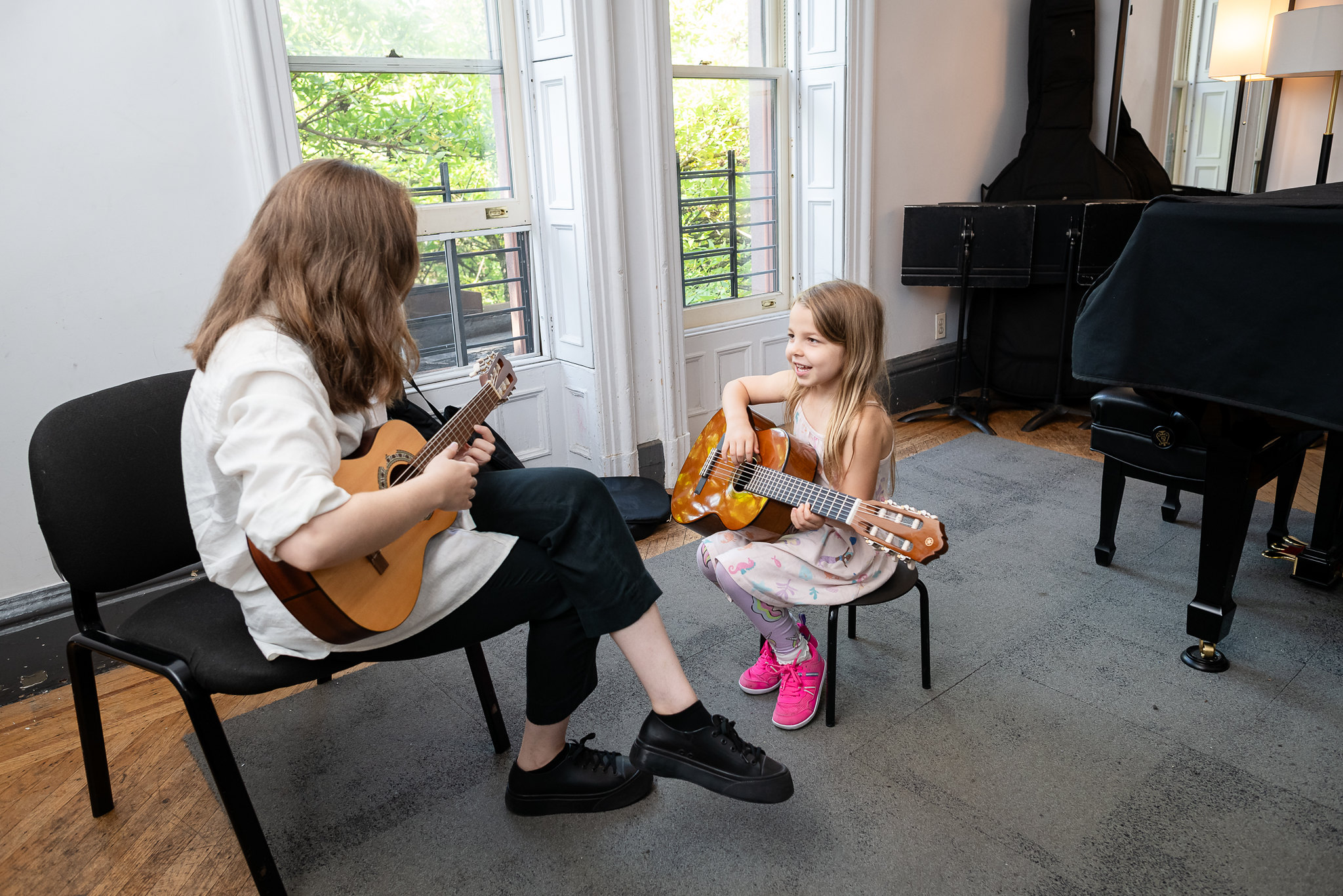 A student and teacher playing guitar together