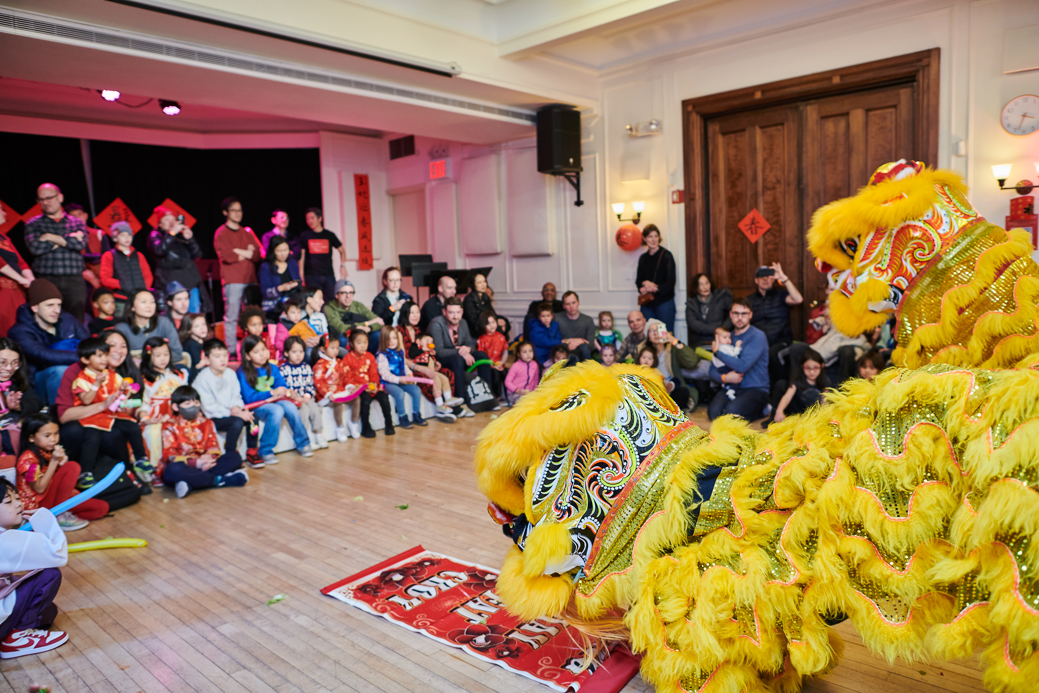 Three performers standing in front of an orchestra in a high school gym
