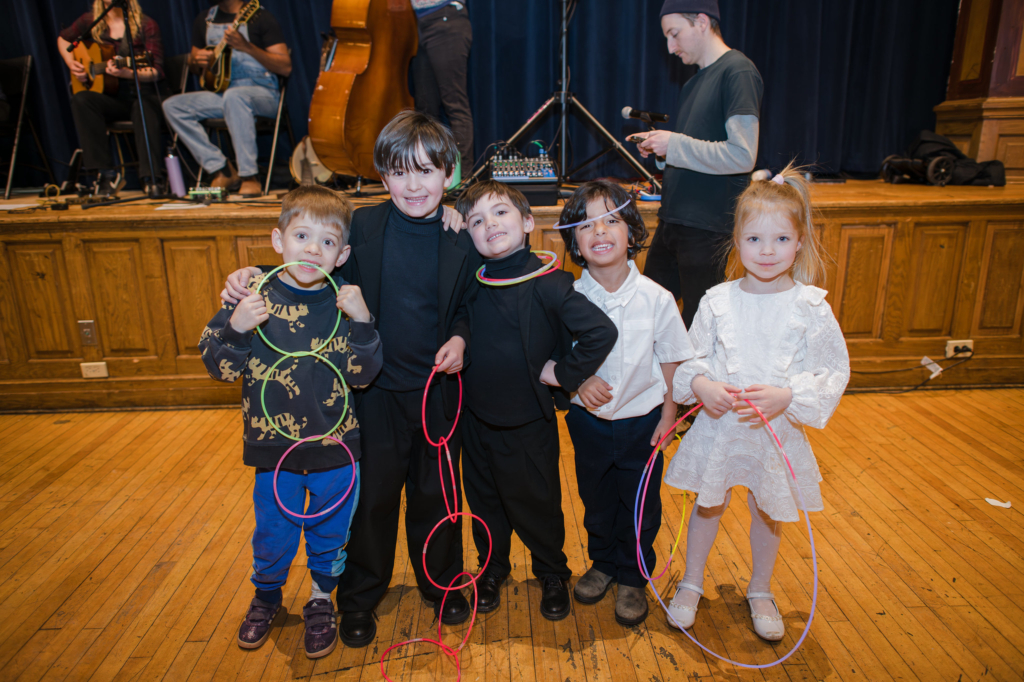 Four Suzuki students smiling at the camera and holding glow sticks
