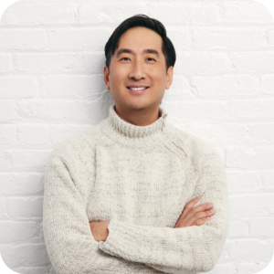 A headshot of Frederick Tang against a white brick background