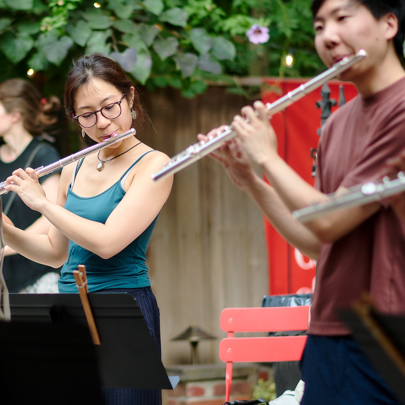 Two BKCM students playing the flute in the garden.